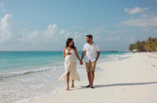 babymoon na praia com casal grávido caminhando de mãos dadas antes da chegada do bebê