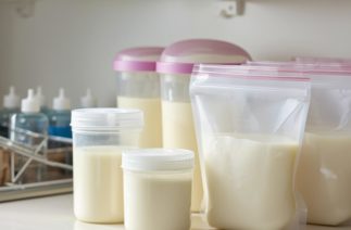 Potes e saquinhos com leite materno armazenado sobre bancada, mostrando formas práticas de conservar o leite materno em casa