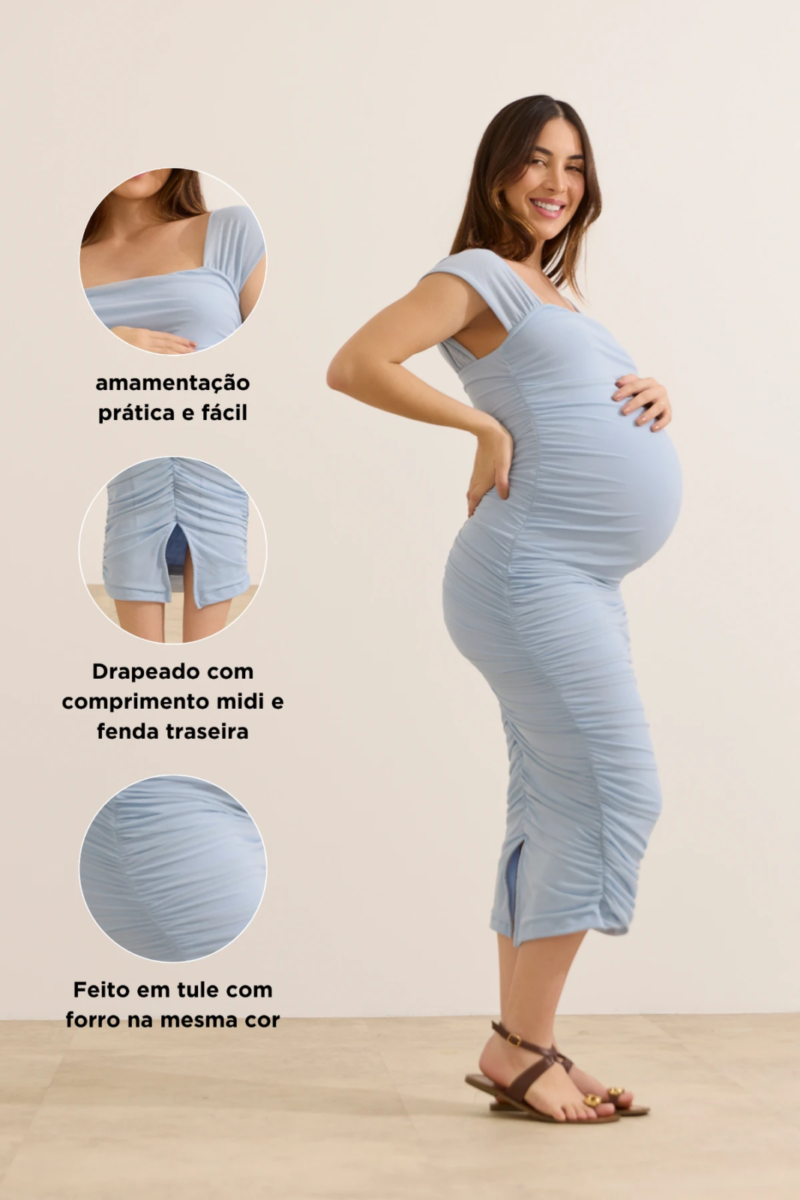 Gestante usando vestido midi azul claro drapeado com alças largas, modelagem ajustada na barriga, fenda traseira e detalhe para amamentação.