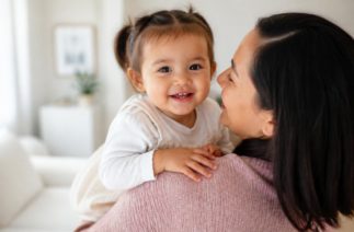 Mãe e criança sorrindo em um abraço carinhoso na primeira infância.