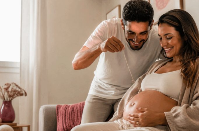 Casal fazendo simpatia para descobrir o sexo do bebê com uma aliança sobre a barriga
